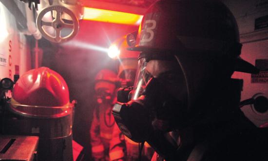 Sailors prepare to enter a smoke-filled space during a general quarters drill