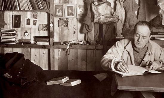 Captain Robert Falcon Scott writing in his diary in his Cape Evans hut