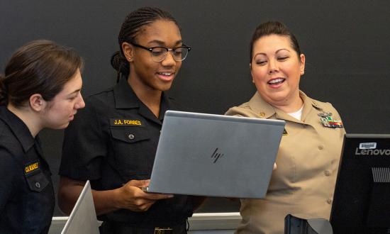 Midshipmen confer with a professor at the U.S. Naval Academy.
